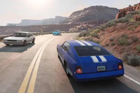 Trzy samochody jadą krętą drogą przez pustynny krajobraz. Zastanawiasz się, ile kosztuje BeamNG Drive na Steam?