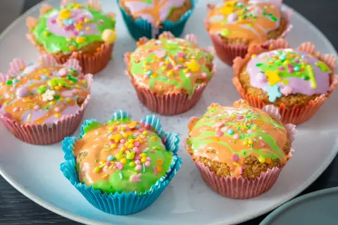 Bunte Karotten Muffins mit Zuckerguss und Streuseln, perfekt für Ostern.