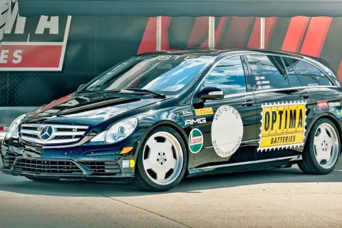 Czarny Mercedes R-klasy z naklejkami "OPTIMA BATTERIES", "AMG", "WEISTEC". To auto z serii r63.