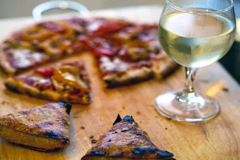 En saftig pizza med ett glas vitt vin till. Perfekt för en mysig kväll.