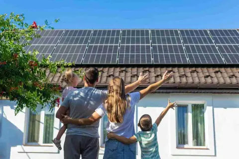 Familia celebra el **revamping fotovoltaico** de su hogar, con paneles solares en el tejado y un futuro brillante.