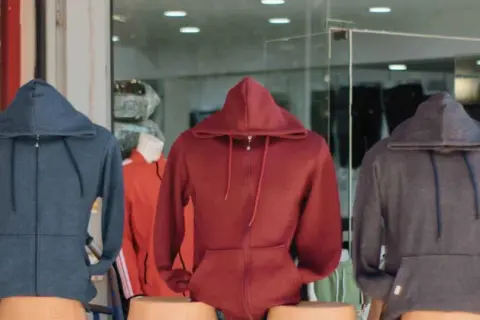 Drei Hoodies in Blau, Rot und Grau. Ein Sweatshirt ist ein bequemes Kleidungsstück mit Kapuze.