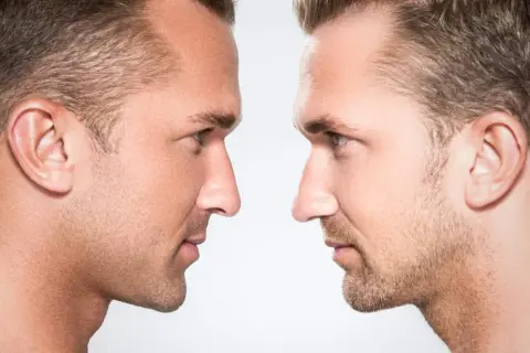 Dos perfiles masculinos enfrentados, resaltando la masculinidad facial con detalles de piel y vello.