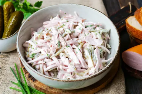 Schmackhaftes Fleischsalat-Rezept in einer Schüssel, garniert mit Schnittlauch und Gewürzgurken. Perfekt für ein schnelles Mittagessen.