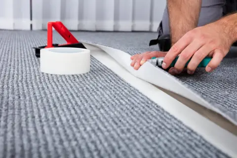 Händer som syr ihop trasmattor med en mattkniv och tejp.