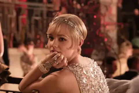 Elegancka kobieta w błyszczącej sukni i opasce na głowie, uosobienie wielki gatsby stylizacja, z diamentową biżuterią.