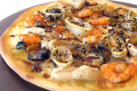 Une délicieuse pizza fruit de mer, garnie de crevettes, moules et calamars, saupoudrée d'herbes.