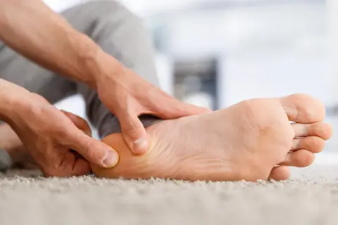Main d'une personne massant la plante du pied pour soulager douleur.