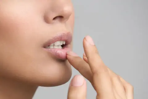 Une femme applique un baume sur ses lèvres. Si vous avez des lèvres gercées, que faire ? Hydratez-les !