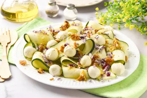 Deliciosa ensalada de calabacín en cintas, con bolitas de mozzarella, nueces y cebolla morada. Un plato fresco y ligero.