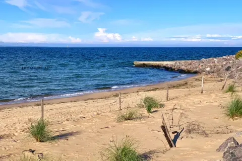 Plaża na półwyspie Św. Wawrzyńca z kamiennym falochronem i błękitnym morzem.