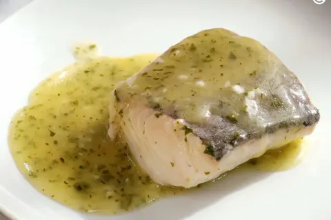 Filete de pescado blanco bañado en una sabrosa salsa verde, con hierbas picadas y un toque de ajo.