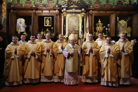 Biskup w otoczeniu młodych kapłanów w kościele.