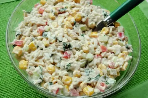 Pyszna sałatka z tuńczykiem, ryżem, kukurydzą, papryką i ogórkiem, polana kremowym sosem. Idealna na szybki lunch.