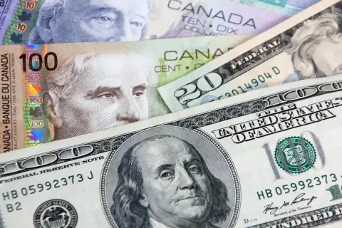 Kanadyjski dolar i amerykańskie banknoty, w tym 100 dolarów kanadyjskich i 100 dolarów amerykańskich, tworzą finansową mozaikę.