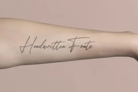 Ein langgezogenes Schrift Tattoo mit dem Schriftzug "Handwritten Fonts" auf einem Arm.