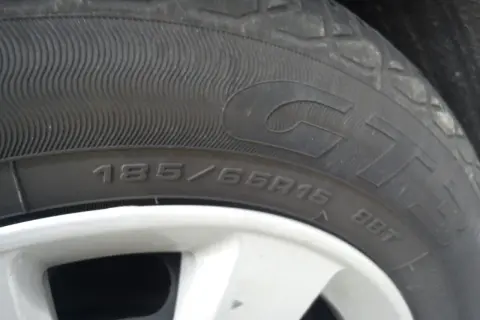 Gros plan sur un pneu rechapé avec inscription 185/65R15. La jante est visible en bas.