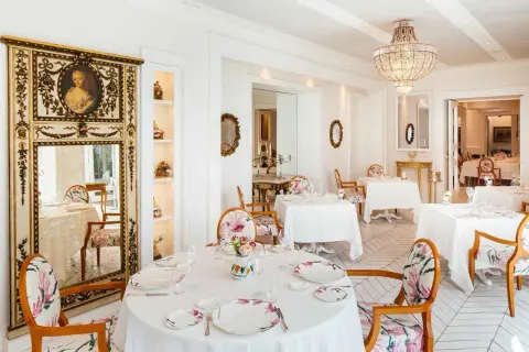 Eleganza e raffinatezza nel ristorante Don Alfonso, dove le stelle Michelin brillano in un ambiente da sogno con arredi floreali e un maestoso lampadario.
