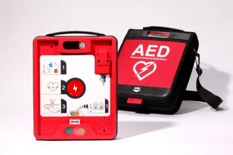Czerwony defibrylator AED i torba z napisem AED. Urządzenie gotowe do użycia w przypadku nagłego zatrzymania krążenia, gdy występuje asystolia.