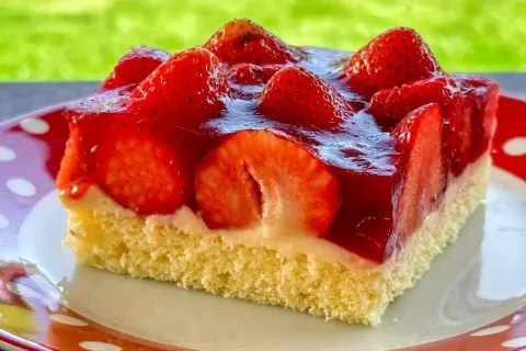 Ein Stück saftiger, **schneller Erdbeerkuchen vom Blech ohne Pudding**, belegt mit frischen Erdbeeren und glänzendem Tortenguss.