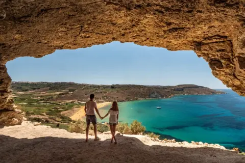 Para w jaskini podziwia widok na turkusowe morze i plażę. Malta pogoda kwiecień idealna na zwiedzanie.