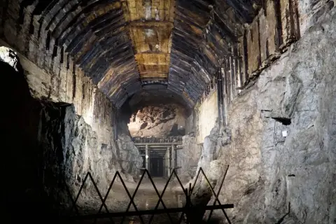 Mroczny tunel kopalni w **Przytkowicach**, z drewnianym stropem i kamiennymi ścianami, prowadzi w głąb ziemi.