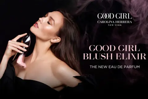 Kobieta zmysłowo wącha perfumy Carolina Herrera Good Girl Blush Elixir w różowym flakonie w kształcie szpilki.
