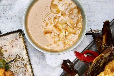 En krämig tahini-sås med kokosflingor, bredvid grillspett med kyckling och grönsaker samt ugnsbakad aubergine och paprika.