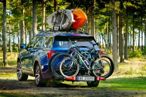 Gotowi na przygodę! Błękitny SUV z rowerami na bagażniku i kajakami na dachu, idealny na pętlę bieszczadzką.