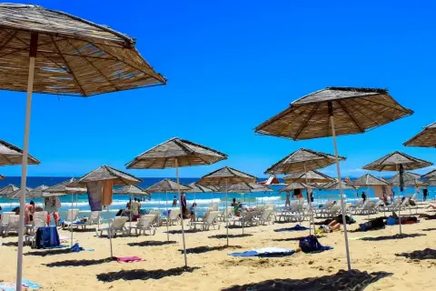 Słoneczna plaża w Bułgarii, pełna leżaków i parasoli. Ludzie odpoczywają, ciesząc się wakacjami. Czy w Bułgarii jest bezpiecznie? Tak, to popularny i bezpieczny kierunek turystyczny.