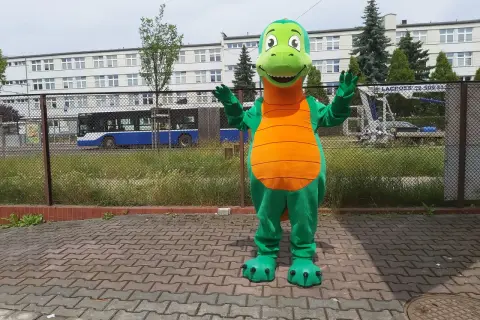 Zielony strój smoka z pomarańczowym brzuchem, stojący na chodniku.