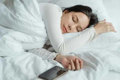 A woman sleeps peacefully, perhaps a natural short sleeper, with her phone nearby.