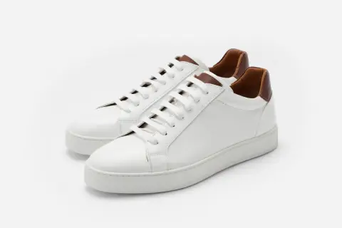 Sneakers bianche in pelle con dettagli marroni. Il loro significato è comfort e stile, perfette per ogni occasione.