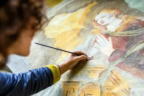 Restauration d'une vieille peinture qui sent mauvais, une main délicate redonne vie à une fresque ancienne.