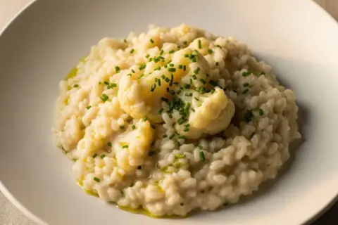 Cremoso risotto de coliflor, coronado con floretes tiernos y cebollino fresco. Un plato reconfortante y lleno de sabor.