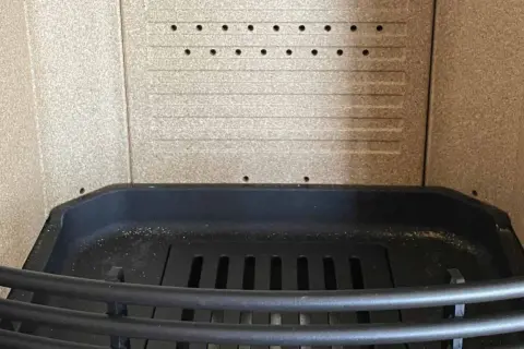 Intérieur d'un poêle, prêt à remplacer la vermiculite par fonte. Grille en fonte et parois texturées.