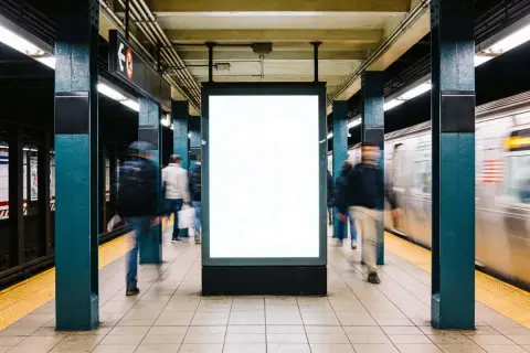 Gente se mueve rápido en el metro de Nueva York, pasando un anuncio en blanco.