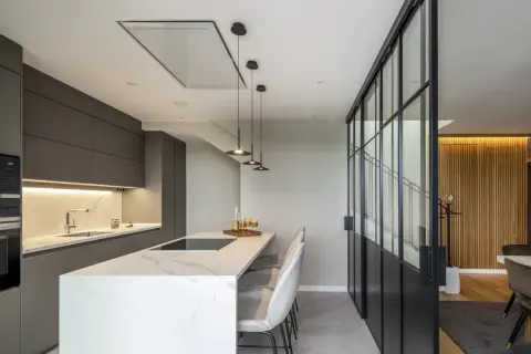 Cocina moderna con isla, campana extractora empotrada en el techo y diferentes tipos de campanas extractoras visibles.