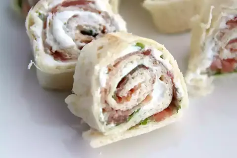 Rouleaux de pain de mie garnis de fromage frais et de jambon, coupés en tronçons pour un apéritif gourmand.