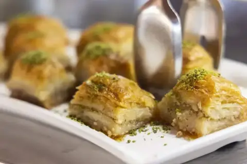 Słodka baklava, co to? Warstwy ciasta filo, orzechów i syropu, posypane pistacjami. Idealna na deser.