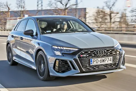 Szary Audi RS3 na drodze. Kierowca w okularach. Sprawdź audi rs3 cena i osiągi.