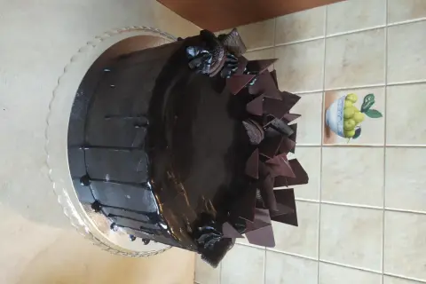 Czekoladowy tort z polewą, czekoladowymi płatkami i ciasteczkami Oreo.