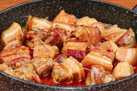 Soczysty boczek duszony z cebulą w sosie, podany w głębokiej patelni. Aromatyczne danie, które rozpływa się w ustach.