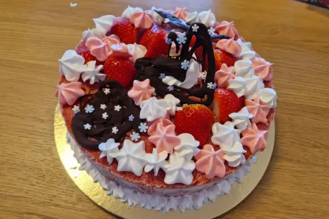 En jordgubbstårta med klassiska tårtor namn, dekorerad med maränger, choklad och färska jordgubbar.