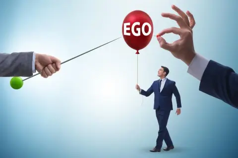 Mężczyzna z balonem "EGO" w ręku, symbolizujący cechy narcyza, zagrożony przez szpilkę.