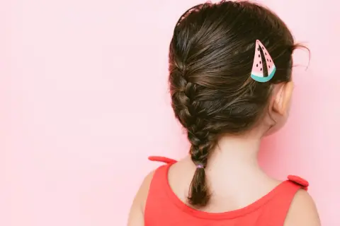 Peinados para niñas: una trenza lateral con un pasador de sandía, ideal para un día soleado.