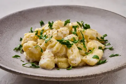Puszyste gnocchi w kremowym sosie, posypane świeżą natką pietruszki. Idealny sos do gnocchi na szybki obiad.