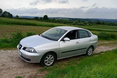 Srebrny Seat Cordoba na tle zielonych pól i pagórków.