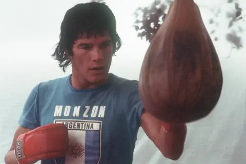Carlos Monzón, the legendary boxer, trains with a speed bag, his focus intense.