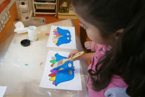 Niña pinta pájaros de colores, preparándose para un día de la paz para niños.